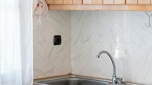 Una cocina con armarios de madera, un lavamanos de acero inoxidable y un salpicadero de mármol.