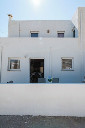 A two-story building with a flat facade, a central entrance, and two windows on the ground floor. - Seafront maisonettes by TinosStay (Kardiani)