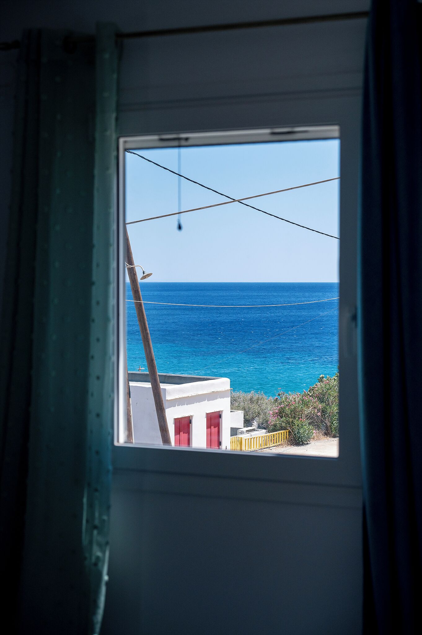 Una finestra con vista sul mare e un edificio con porte rosse.