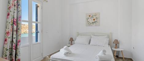 Een slaapkamer met een bed, twee nachtkastjes, een lamp en een raam met gordijnen.
