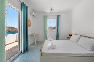 Habitación de hotel con cama, un escritorio pequeño, ventana con cortinas y vista al mar.