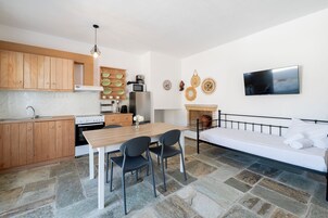 Un espacio habitable compacto con kitchenette, comedor, sofá y televisor.
