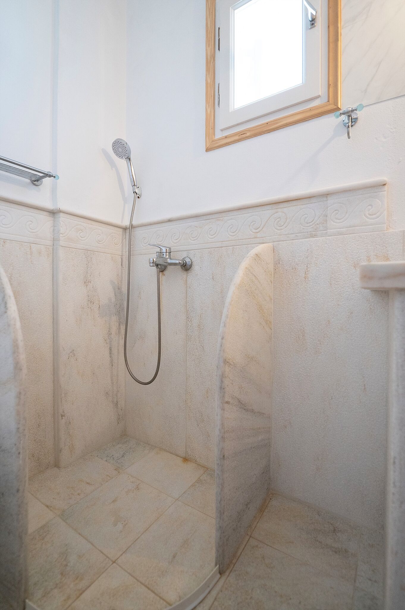 Une salle de bain avec une douche, une fenêtre et un porte-serviettes.