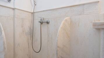 Une salle de bain avec une douche, une fenêtre et un porte-serviettes.