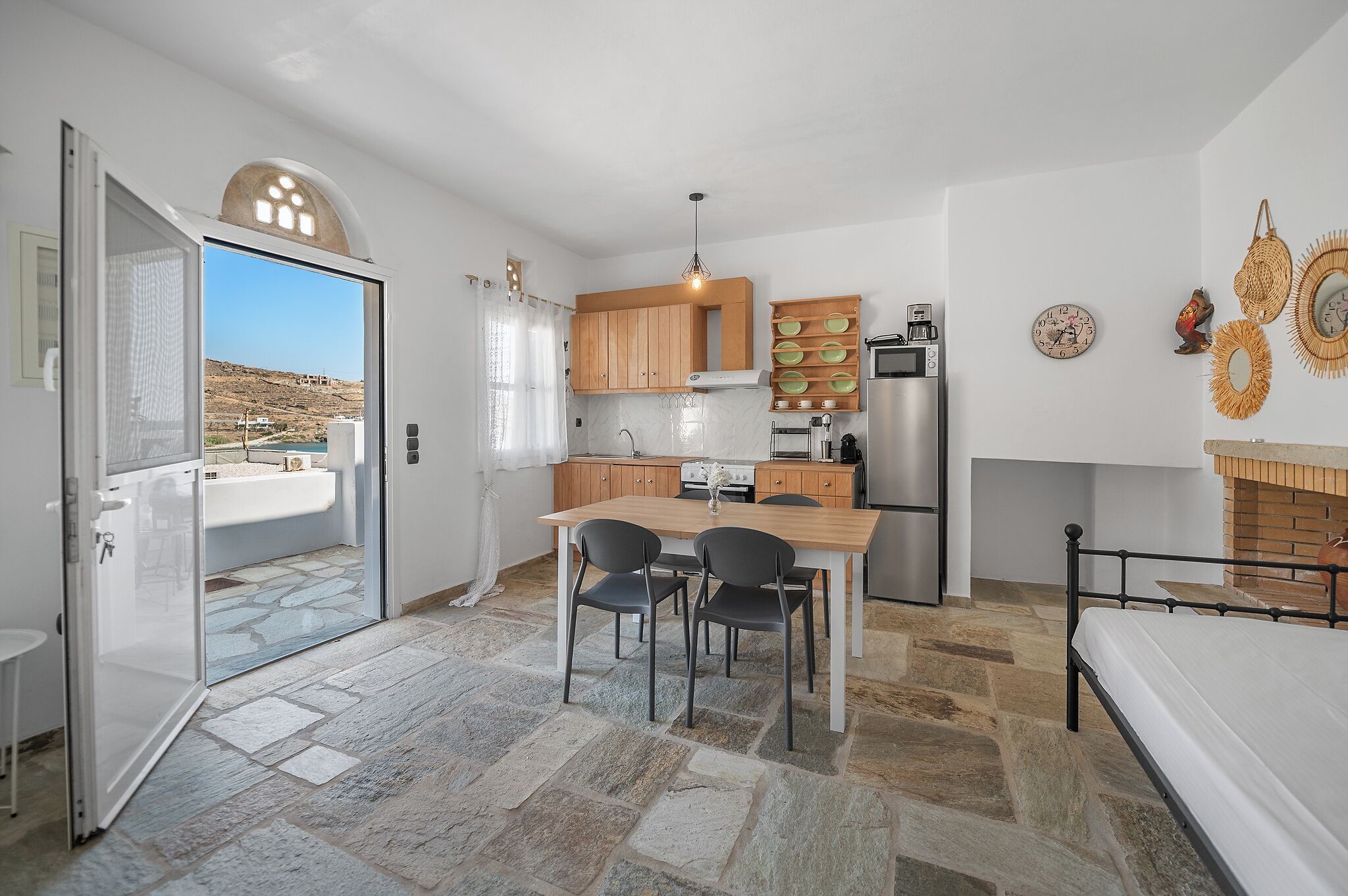 A compact kitchen with a dining area, a refrigerator, a stove, and a view through an open door.