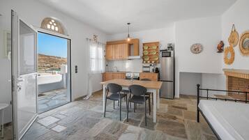 A compact kitchen with a dining area, a refrigerator, a stove, and a view through an open door.