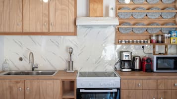 Una cocina con armarios de madera, protector contra salpicaduras de mármol, un lavamanos de acero inoxidable, una cafetera, un tostador y un microondas.
