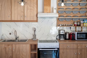 Una cocina con armarios de madera, protector contra salpicaduras de mármol, un lavamanos de acero inoxidable, una cafetera, un tostador y un microondas.