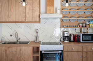Una cocina con armarios de madera, protector contra salpicaduras de mármol, un lavamanos de acero inoxidable, una cafetera, un tostador y un microondas.