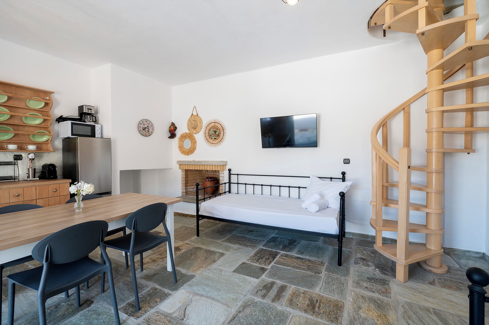Une chambre à coucher de taille réduite, comprenant un lit, un téléviseur et un escalier en colimaçon en bois.