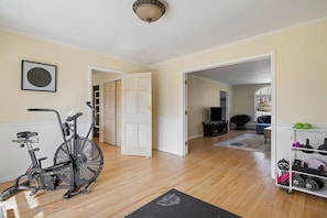 A home interior with an exercise bike, a treadmill, and a home gym setup.