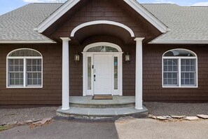 A two-story house with a brown exterior, white trim, and a front porch with a white door. - Luxury Windham Retreat w/ Hot Tub & Fireplace, Mins to Slopes (Windham)