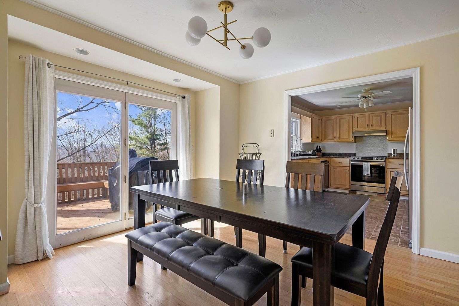A dining area with a table and benches, a kitchen with wooden cabinets, and a sliding glass door leading to an outdoor deck.