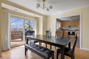 A dining area with a table and benches, a kitchen with wooden cabinets, and a sliding glass door leading to an outdoor deck.