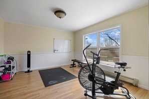 A room with a stationary bike, a whiteboard, and a window with a view of a deck. - Luxury Windham Retreat w/ Hot Tub & Fireplace, Mins to Slopes (Windham)