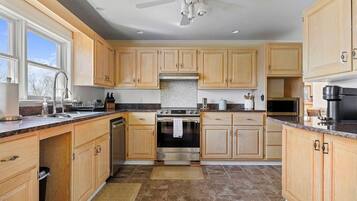 A kitchen with wooden cabinets, a stainless steel oven, a microwave, and a ceiling fan.
