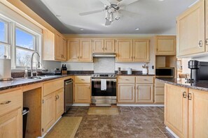 A kitchen with wooden cabinets, a stainless steel oven, a microwave, and a ceiling fan. - Luxury Windham Retreat w/ Hot Tub & Fireplace, Mins to Slopes (Windham)
