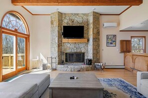 A living room with a stone fireplace, a flat-screen TV, a sofa, and a coffee table.