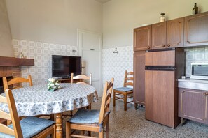 Eine kompakte Küche mit Esstisch, Stühlen, Kühlschrank, Mikrowelle und Fernseher.