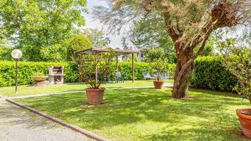 A well-maintained garden with a gazebo, potted plants, and a barbecue area.