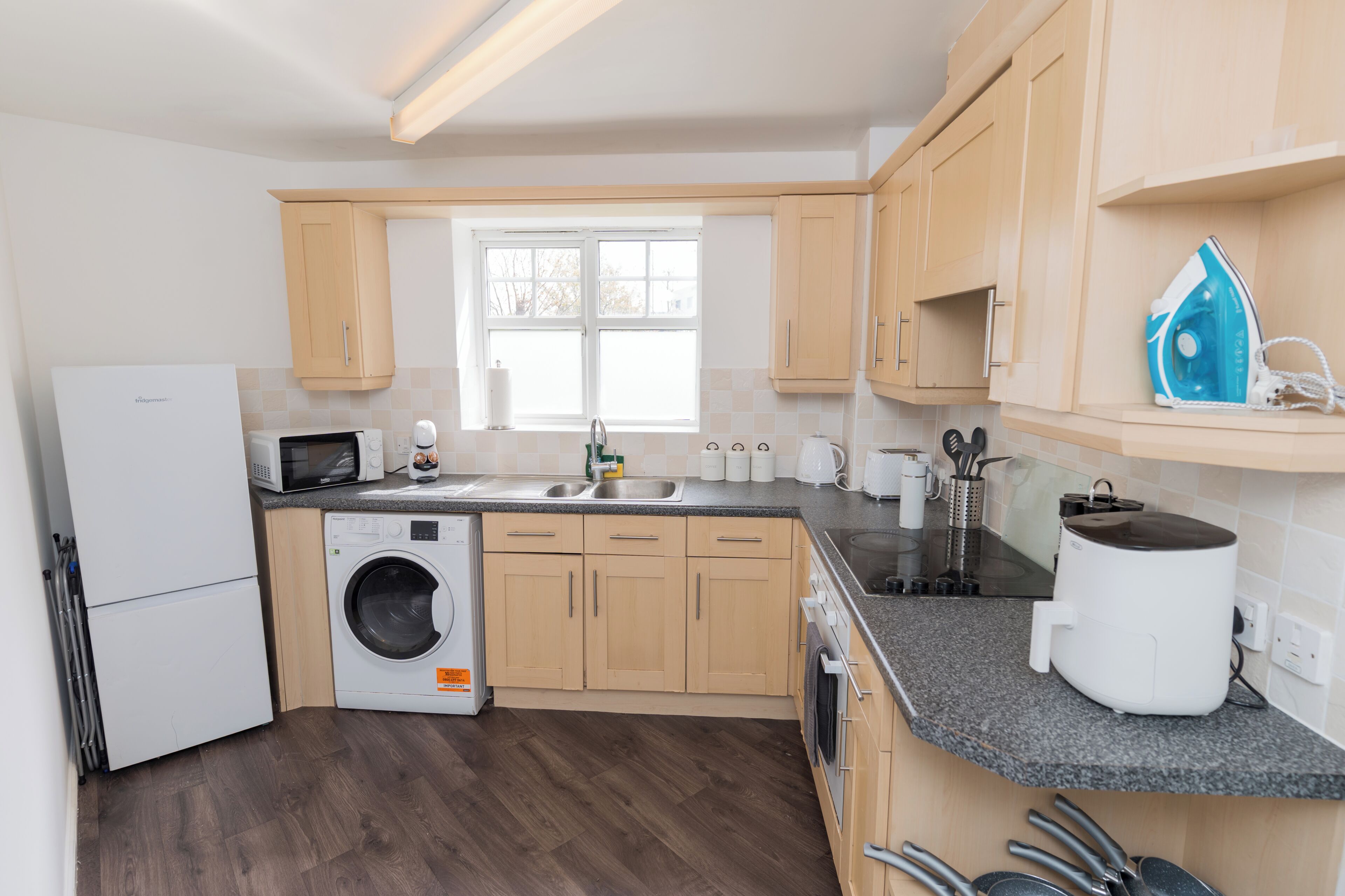 A modern kitchen with a built-in washer, a microwave, and a coffee machine.