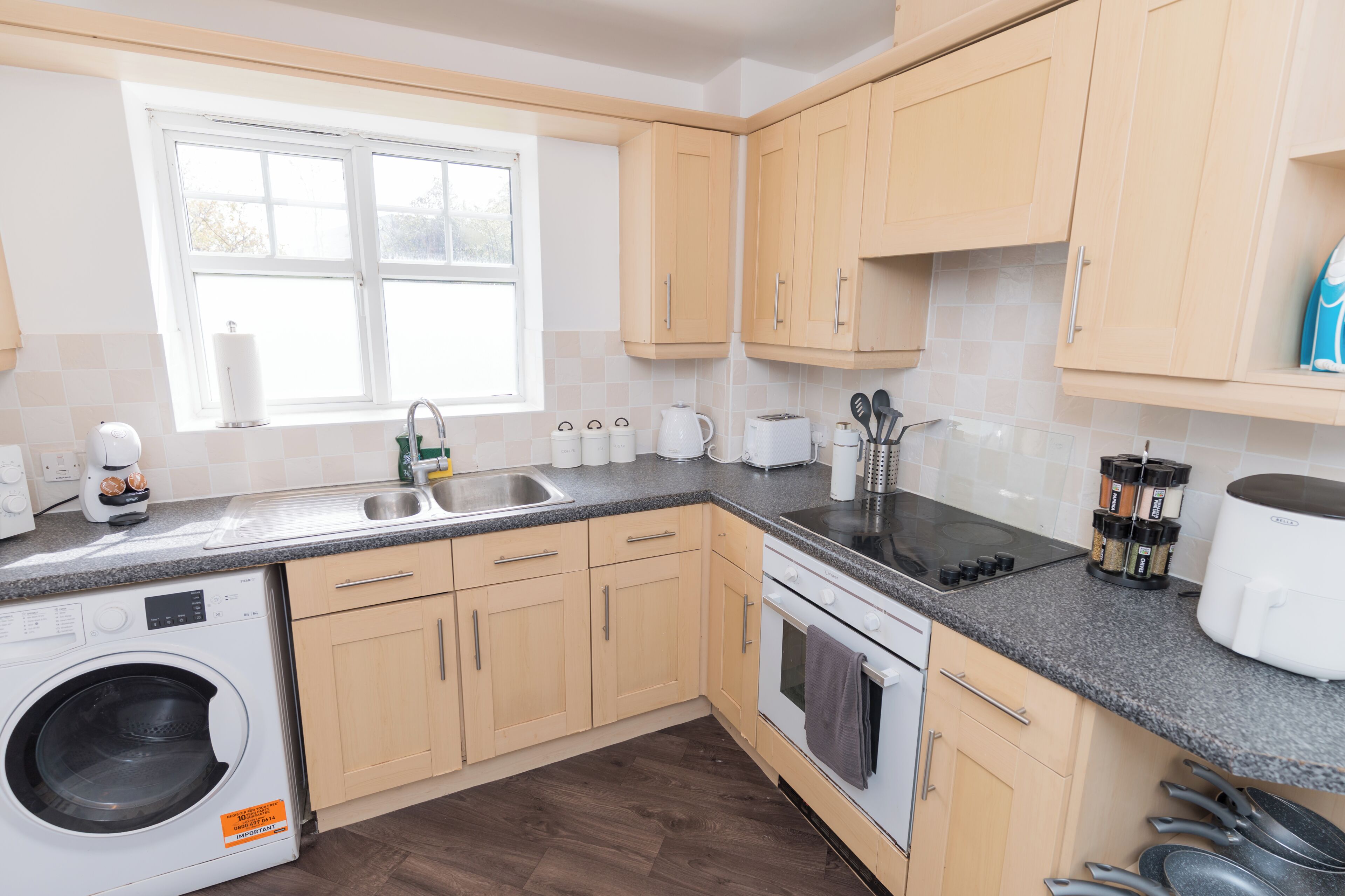 A modern kitchen with a built-in washing machine, stainless steel sink, and a stove.