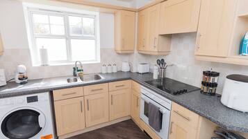 A modern kitchen with a built-in washing machine, stainless steel sink, and a stove.