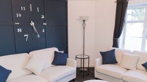 A modern living room with two white sofas, a round coffee table, a floor lamp, and a wall clock. - Boutique 2-Bed Apartment in Wolverhampton Centre (Wolverhampton)