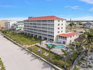 Un hôtel doté d’une piscine, de plusieurs étages et d’un toit rouge.