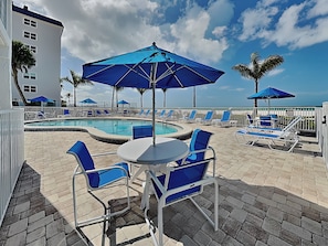 Un espace aménagé au bord de la piscine, avec des chaises longues, des parasols et une piscine.