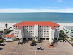 A multi-story hotel with a red roof, parking lot, and a view of the beach. - Pointe South 401 | Resort Views + Pool (Fort Myers Beach)