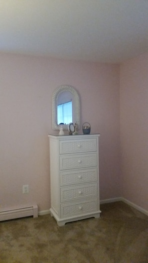 A white dresser with a mirror and a small basket against a pink wall. - Cozy 2-bedroom house in welcoming Spring Lake with AC (Spring Lake)