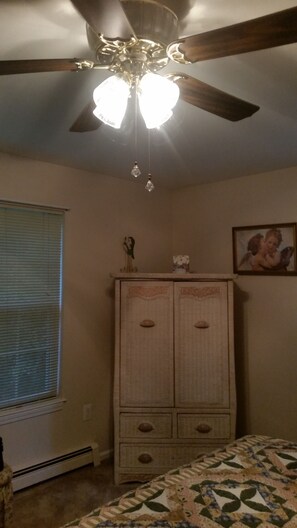 A bedroom with a ceiling fan, a bed, a dresser, and a window with blinds. - Cozy 2-bedroom house in welcoming Spring Lake with AC (Spring Lake)