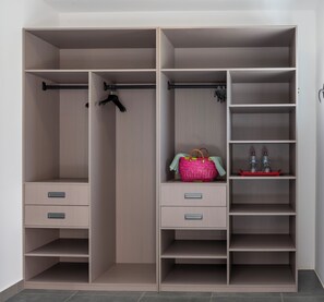 A walk-in closet with open shelving, a hanging rod, and drawers. - Ankomba Hotel (Nosy Komba)