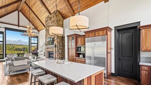 Un'ampia cucina con una grande isola, pensili in legno e una parete decorativa in pietra.