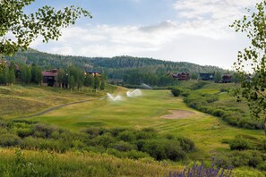 Ein Golfplatz mit mehreren Häusern im Hintergrund und blauem Himmel.