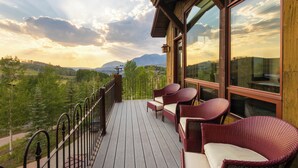 Un terrazzo in legno con mobili in vimini e vista su un paesaggio montuoso.