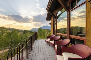 Eine Holzterrasse mit Korbmöbeln und Blick auf eine gebirgige Landschaft.
