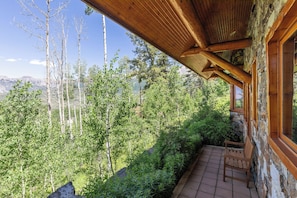 Un balcon en bois offrant une vue sur une forêt et des montagnes.