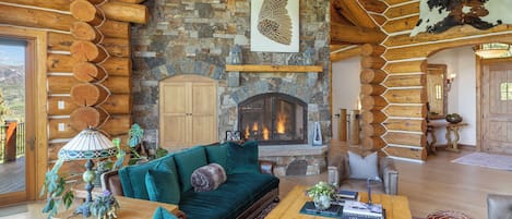 A log cabin interior with a stone fireplace, wooden walls, and a cozy seating area.