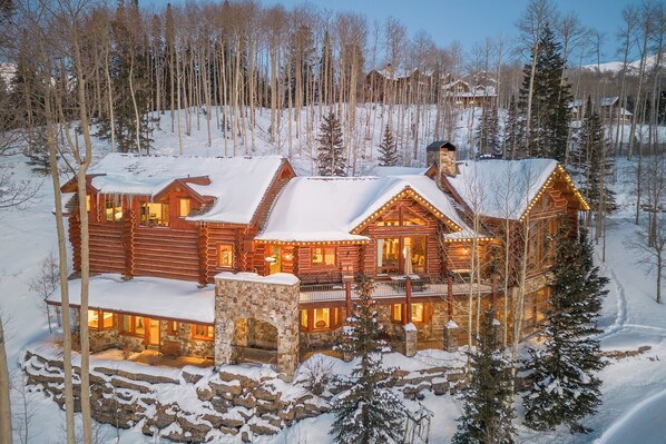 Una baita di legno a più livelli, con fondamenta in pietra e paesaggi innevati.