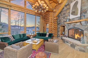 Una sala de estar acogedora con chimenea, ventanas amplias y vistas a las montañas.