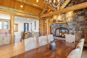 Un tavolo da pranzo in legno con sei sedie, un camino in pietra e un lampadario.
