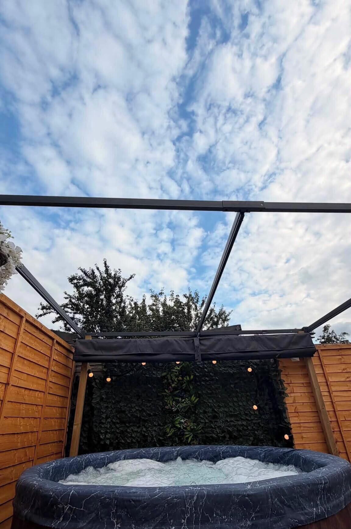 A hot tub under a pergola with a cloudy sky.