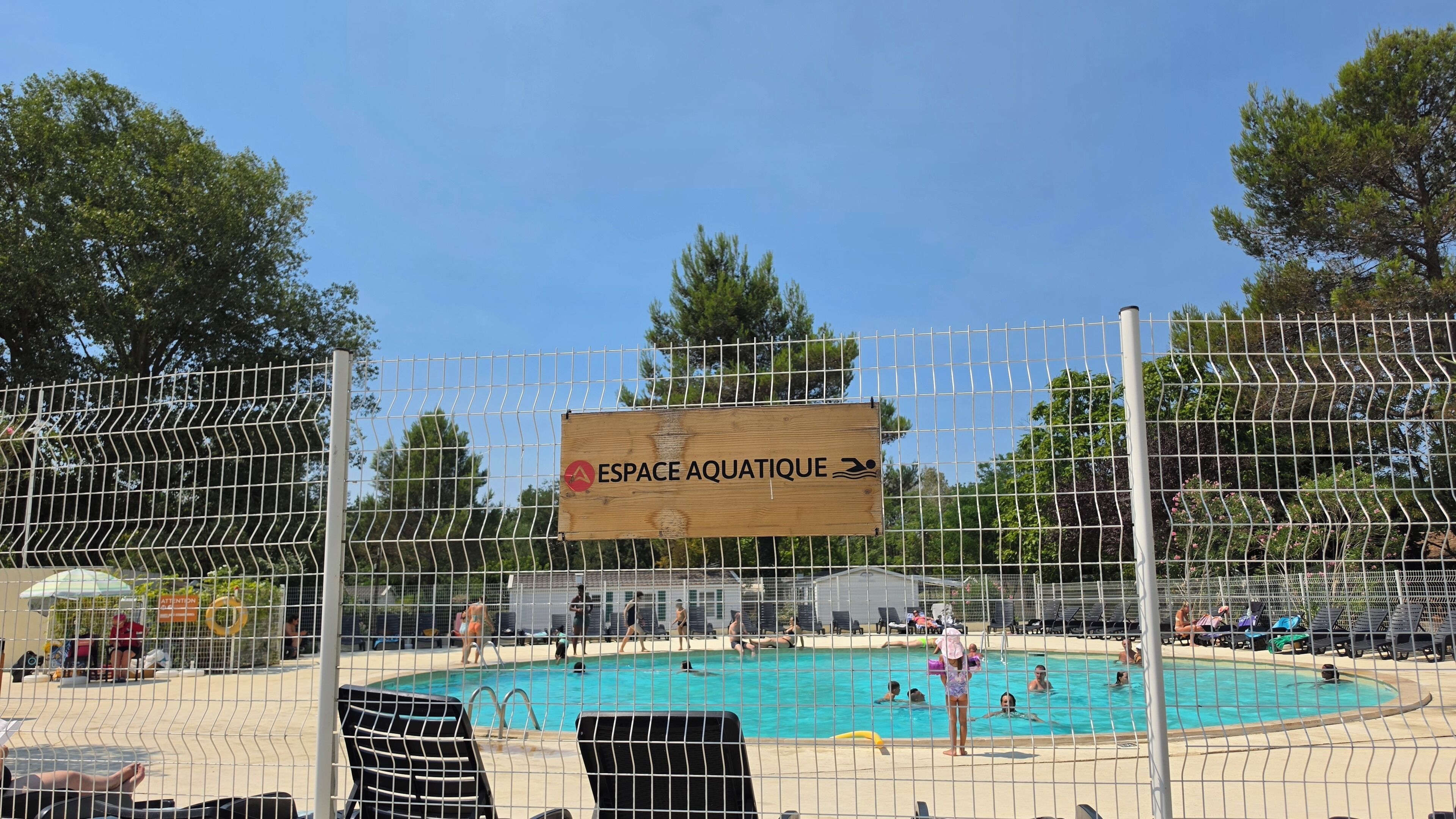 A swimming pool area with a sign reading 'ESPACE AQUATIQUE' and a fenced enclosure.