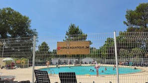 Un espace piscine avec un panneau indiquant « ESPACE AQUATIQUE » et une zone délimitée par une clôture.