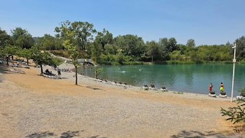 Zona junto al lago con playa de grava, sillas de descanso y vista despejada al agua.
