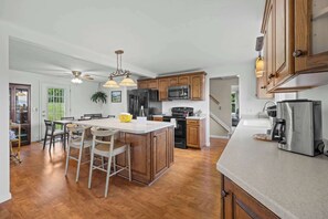 Una cocina moderna con armarios de madera, electrodomésticos de acero inoxidable y una isla central con taburetes de bar.
