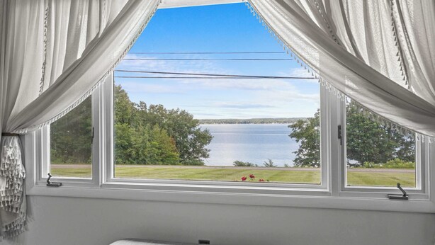 Una habitación con un ventanal grande, una banca y vistas a un lago.