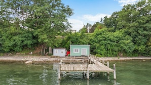 Un muelle que conduce a una cabaña pequeña con vista despejada a un área boscosa.